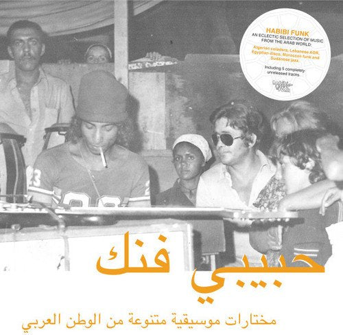 Black and white photo of people in a studio with yellow Arabic text overlay.