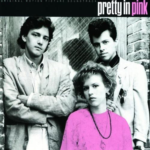 Black and white photo of three young people, with the woman wearing pink.