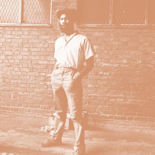 Sepia-toned portrait of a man in work clothes leaning against a brick wall.