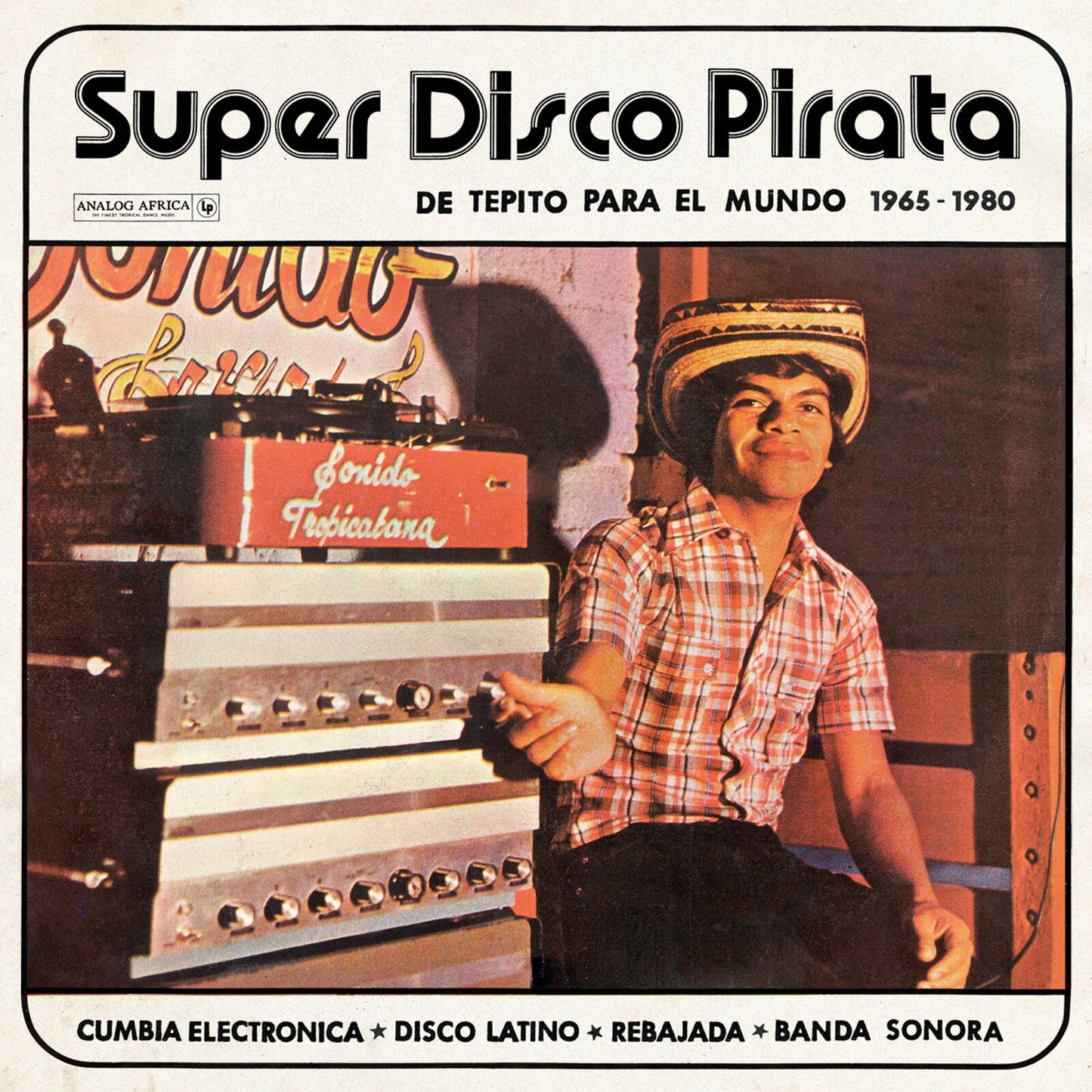 Man in plaid shirt and hat sitting next to audio equipment on vinyl cover.