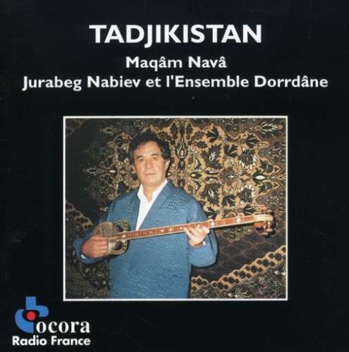 A man in a blue jacket plays a stringed instrument against a patterned background.