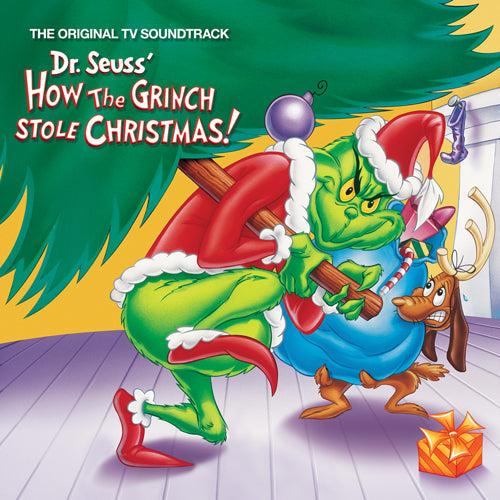 The Grinch in a Santa suit carries a Christmas tree with his dog Max.