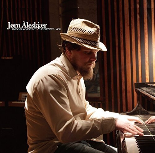 A bearded man in a straw hat plays a piano in a music studio.