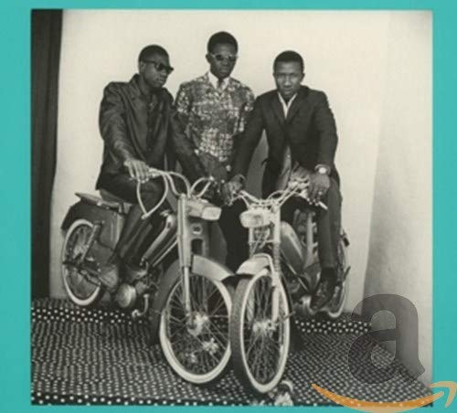 Three men in suits pose on vintage mopeds in a black and white photograph.