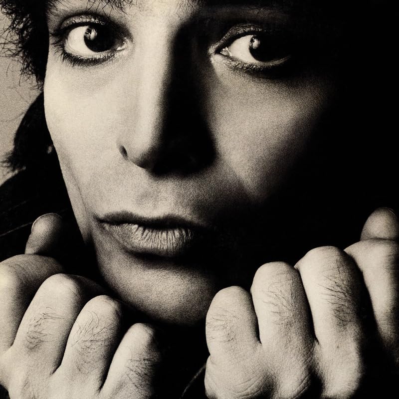 Black and white portrait of Alan Vega, looking directly at the viewer.