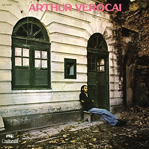 Album cover: man sitting by a building with arched windows.
