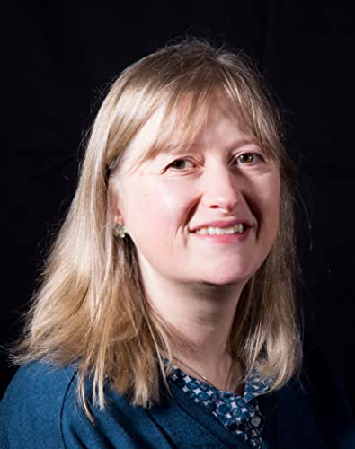 Headshot of a smiling woman with blonde hair against a black background.