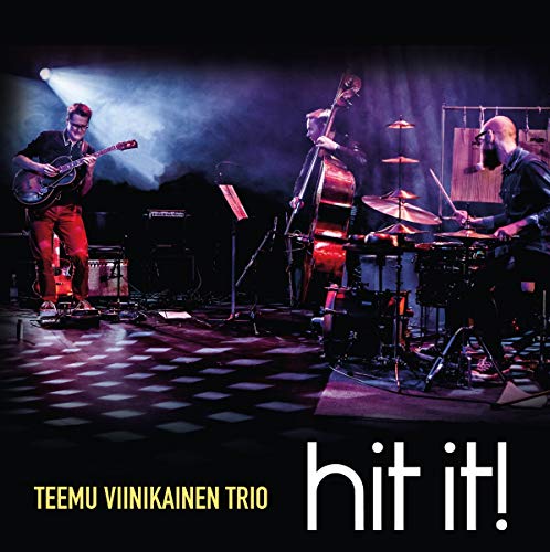 Jazz trio performing on stage with guitar, bass, and drums.