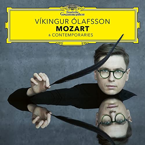 Víkingur Ólafsson wearing glasses and holding a quill, with his reflection below.