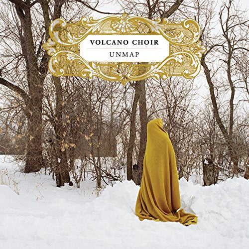 The album cover for "Volcano Choir - Unmap" features a person draped in a yellow fabric, standing in a snowy landscape. Here is a concise, descriptive alt text: A person covered in yellow fabric stands alone in a snowy forest.