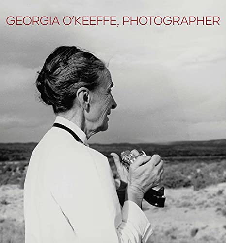 Black and white portrait of Georgia O'Keeffe holding a camera, looking away.