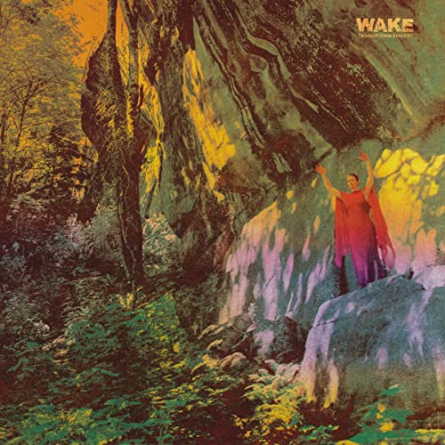CD cover: person in red robe before a rocky, forested cliff.