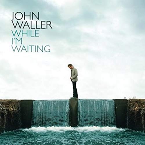 CD cover: man standing on a pillar above a waterfall.