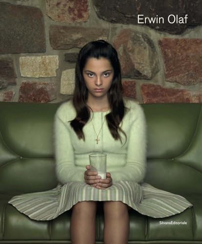 Young woman in a white sweater sits holding a glass of milk.