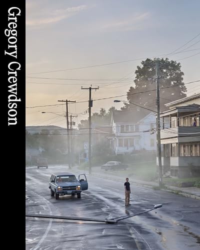 Suburban street scene with a man standing near a parked truck.