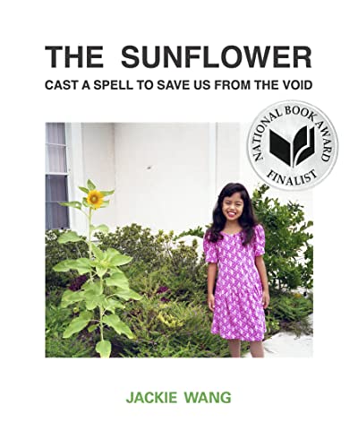 A young girl in a purple dress stands next to a sunflower in a garden.