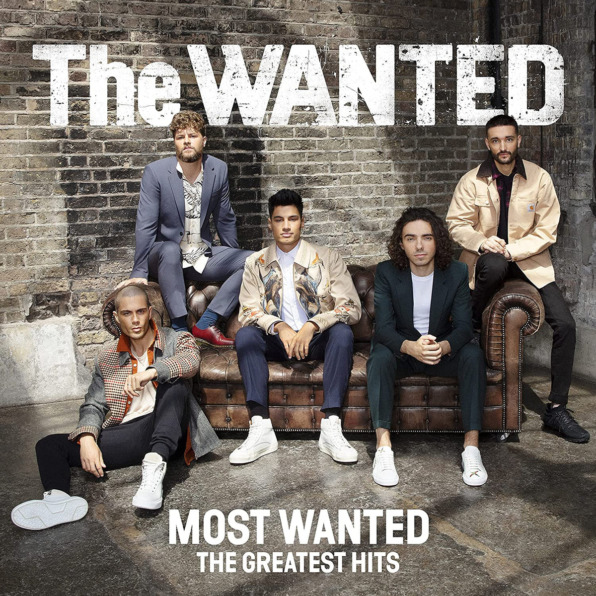 The five members of The Wanted posing on and around a leather sofa.