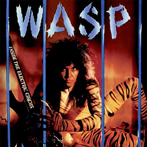 A person with tiger-striped body paint behind blue bars, with the band name WASP above.