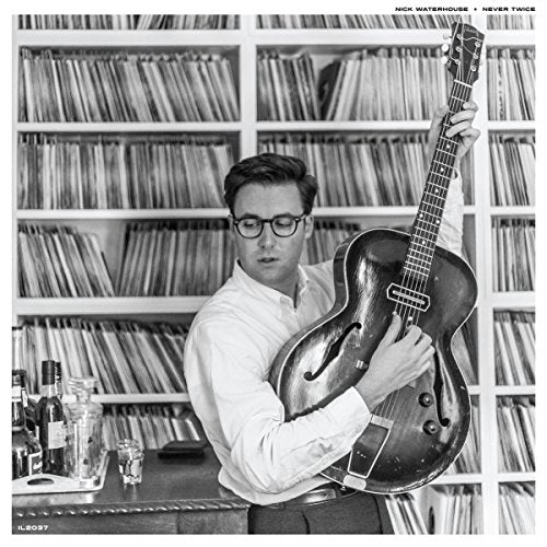 Black and white album cover: man holding guitar in front of vinyl records.