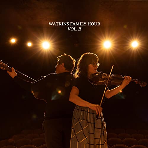 Two musicians with guitar and violin on a stage, album cover.