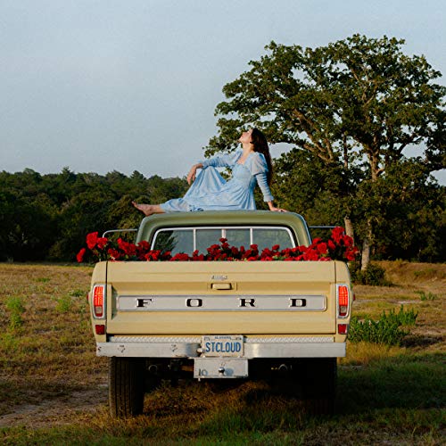 Woman in blue dress sitting on the back of a yellow Ford truck.