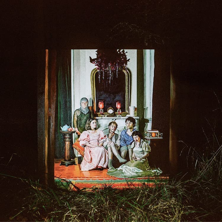 Group portrait in a darkly lit, ornate room with vintage furniture.