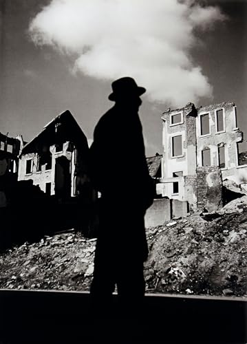 Black and white photo of a silhouetted man before ruined buildings.