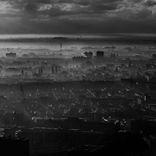 Black and white cityscape under a cloudy, overcast sky.