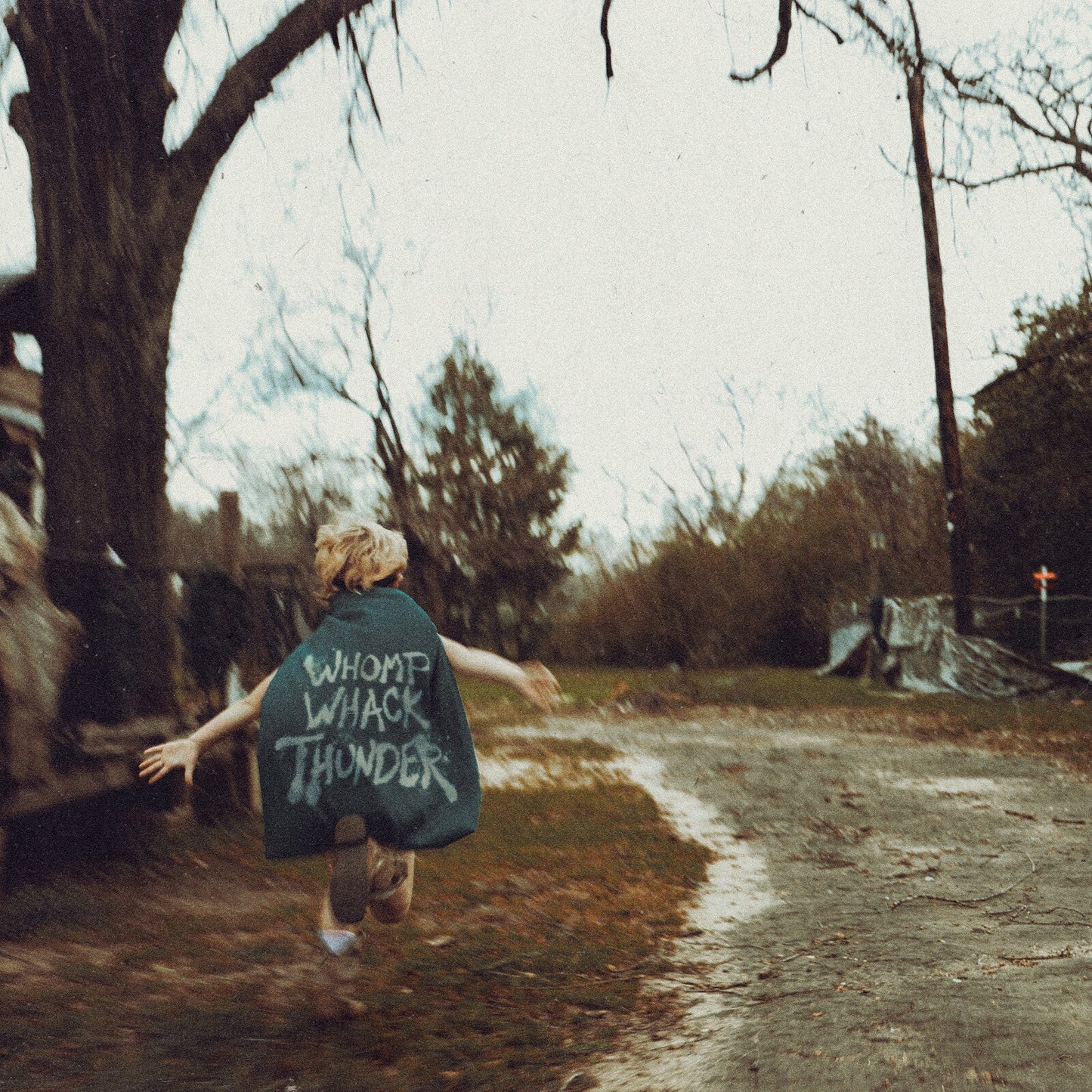 Person with arms outstretched running down a rural dirt road.