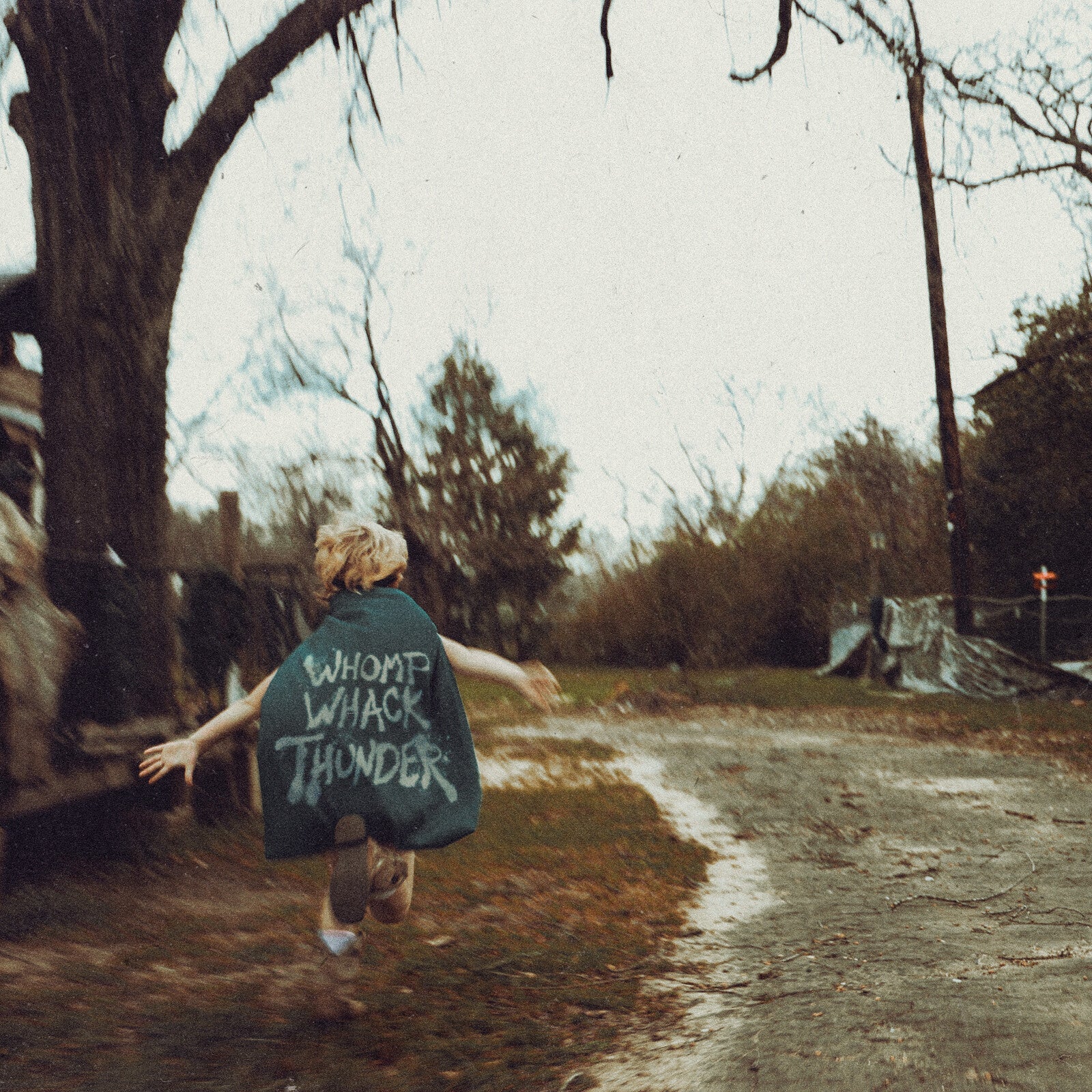 Person with arms outstretched running down a rural dirt road.