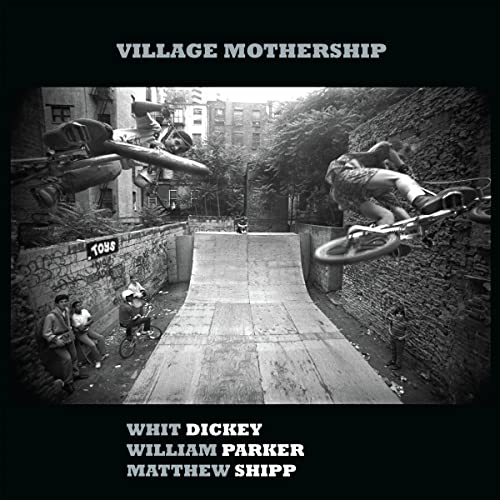 Black and white photo of BMX bikers performing tricks in a city.