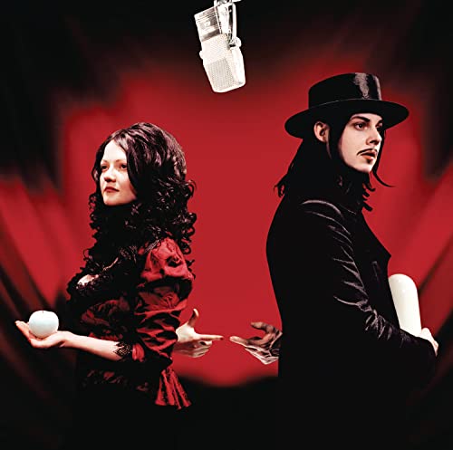 The White Stripes duo with a microphone, against a red, textured background.