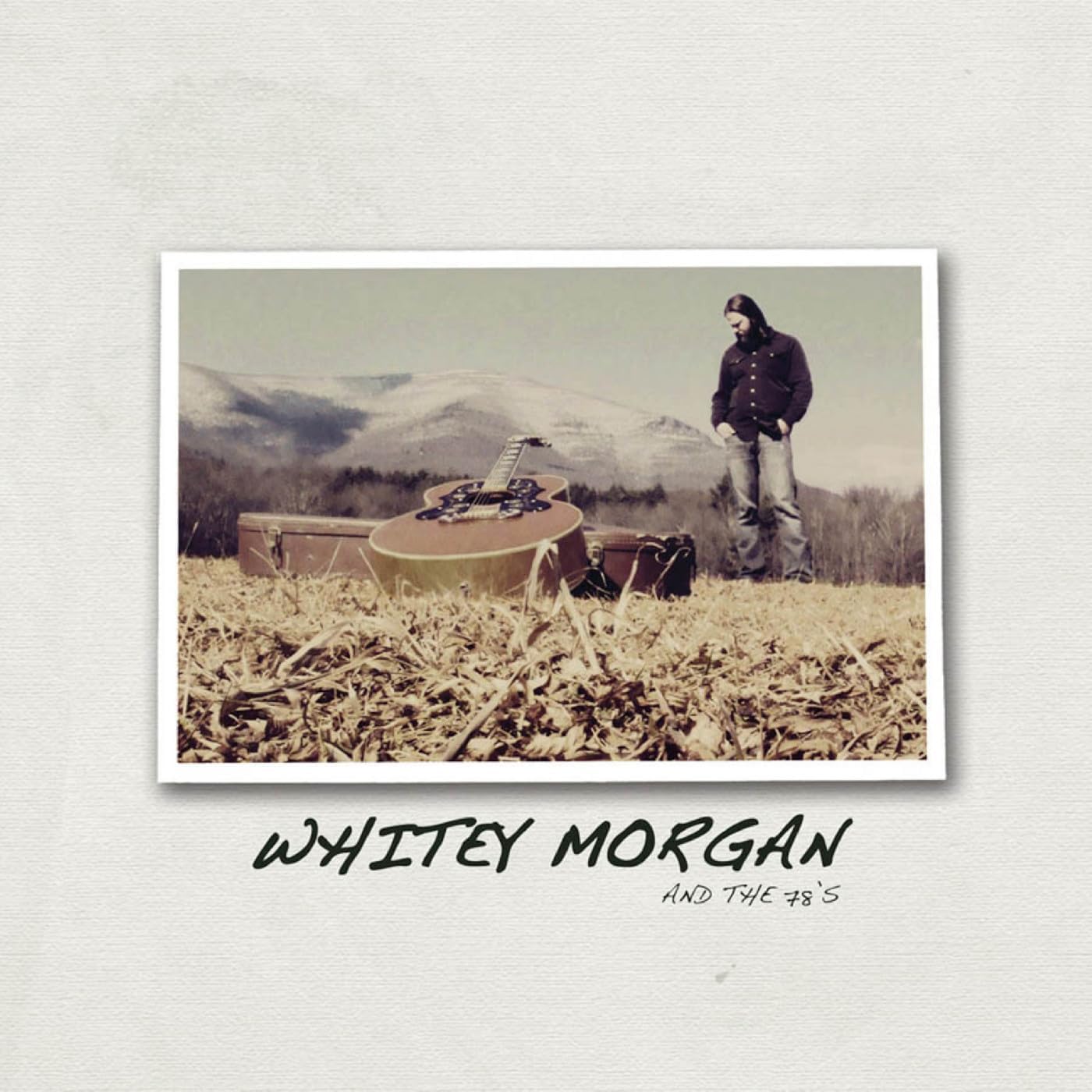Album cover: man with guitar in a field, sepia tone.
