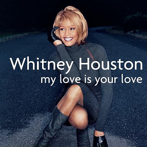 Whitney Houston album cover, smiling, wearing a grey dress and boots.