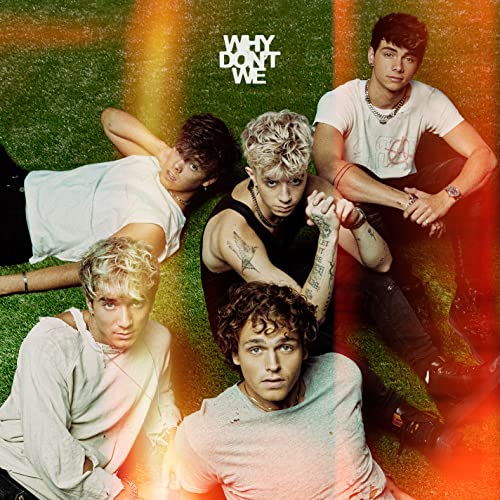 Why Don't We band members posing on artificial green turf.