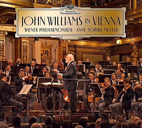 John Williams conducting the Vienna Philharmonic orchestra in a concert hall.