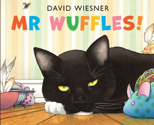 A black cat with yellow eyes lies on a floor surrounded by colorful toys.