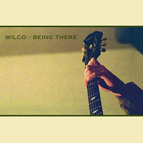The image shows a vinyl record cover for Wilco's "Being There". The concise alt text is: "Vinyl record cover with hand holding a guitar headstock."