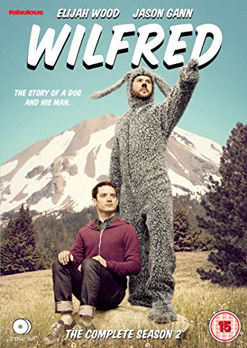 "Man sits beside person in dog costume, with snowy mountains in the background."