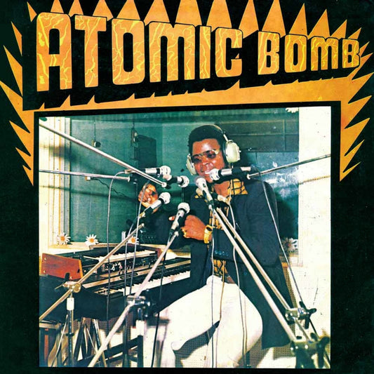 William Onyeabor wearing headphones and sunglasses at a keyboard with microphones in a studio.