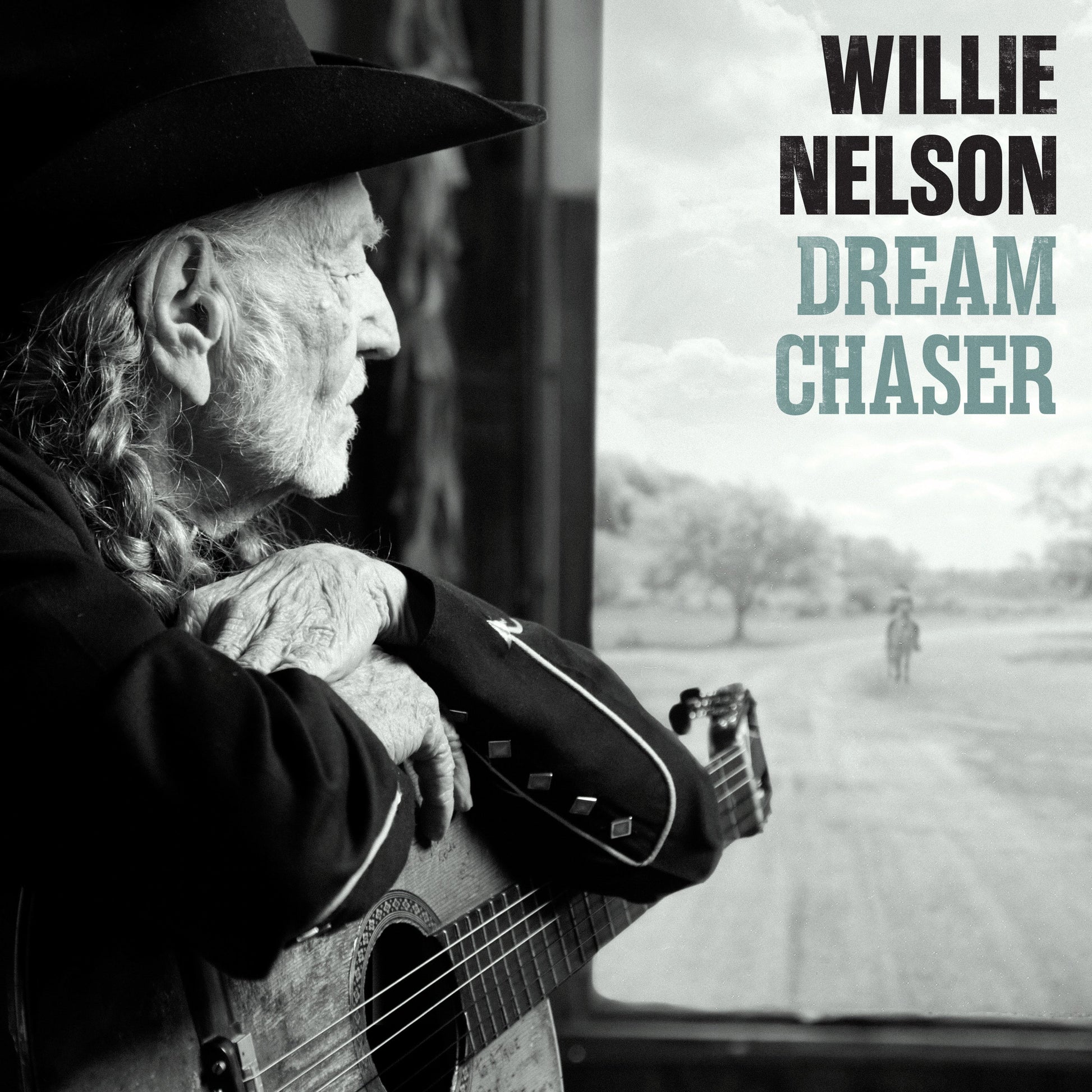 Willie Nelson in a cowboy hat holding a guitar, looking out a window.