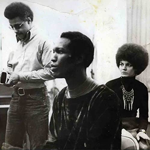 Black and white photo of three people, including a man with glasses and a woman.