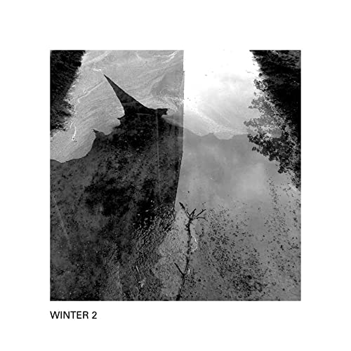 Black and white abstract image of a dark triangular shape over a textured surface.