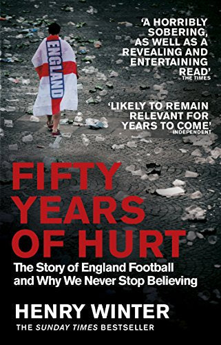 A person draped in an England flag walks through debris on a cobblestone street.
