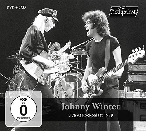 Black and white photo of Johnny Winter and band performing live onstage.