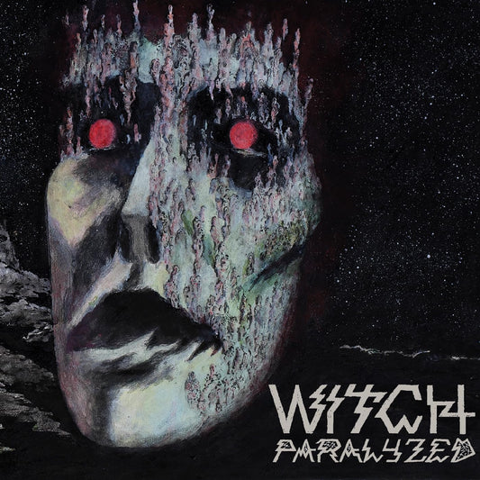 Painted face with red eyes and textured details against a dark background.