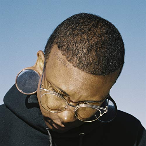 CloseCLCSClose-up of a manS man with short hair wearing glasses and large gauge earrings.