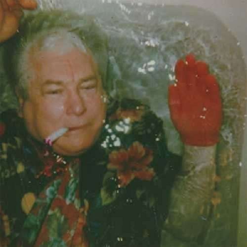 Man in a tub with a red glove and cigarette.