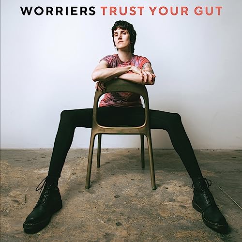 Album cover: person sitting on chair, legs extended, neutral background.