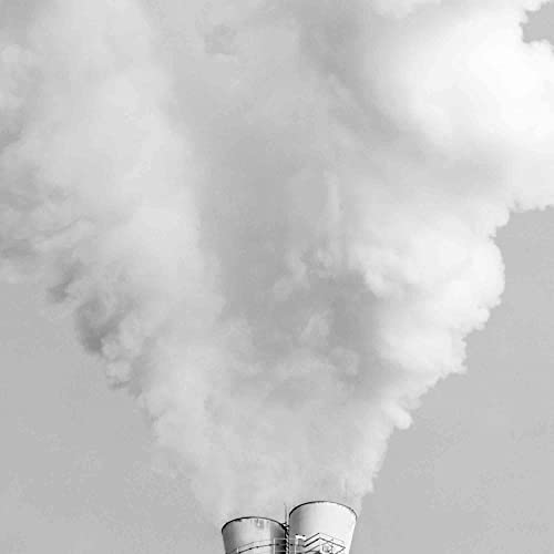 Black and white image of industrial smokestacks emitting a large plume of thick smoke.